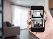 Smartphone displaying live CCTV footage of home interior.
