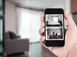 Smartphone displaying live CCTV footage of home interior.